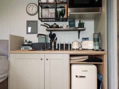 A small kitchen area with a sink utensils appliances and a mini fridge at The Highwood Hut near Liskeard