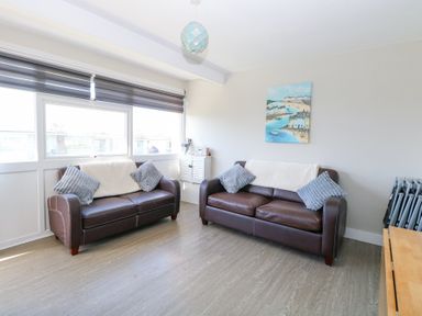 A sitting room with two brown leather sofas and a painting on the wall at Chalet 38 in Hemsby