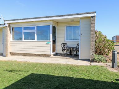 A small patio area with metal table and two chairs outside a bungalow at Chalet 39 in Hemsby