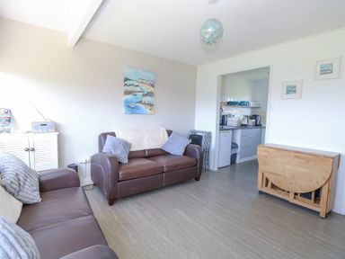 A living room with two brown leather sofas and a wooden foldable table at Chalet 39 in Hemsby