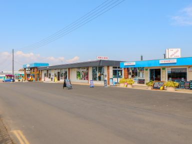 A street view of single story commercial shops including a fish and chips shop and a diner in a coastal town