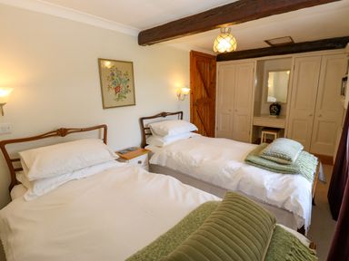 A bedroom with two single beds wooden headboards and green cushions at Pagecroft Cottage in Haydon Bridge