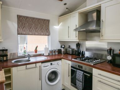 A kitchen with a washing machine sink stove oven and cabinets at Gressingham View Lodge Dock Acres near Carnforth