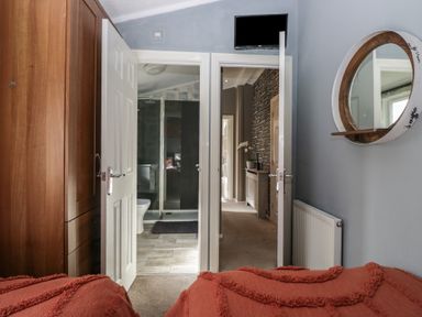 View from a bedroom showing an open door leading to a bathroom and another open door leading to a hallway with a radiator and a round wall mirror at Gressingham View Lodge Dock Acres near Carnforth