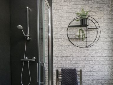 A shower head with glass door and round wall shelf with plants in a bathroom at Gressingham View Lodge Dock Acres near Carnforth
