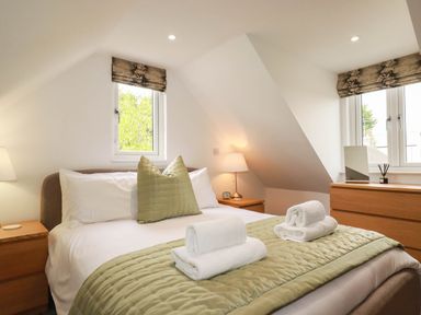 A bedroom with a bed and windows at Tiddlywink near Indian Queens