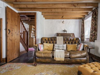 A living room with a sofa and wooden stairs at Cove Cottage Llangrannog