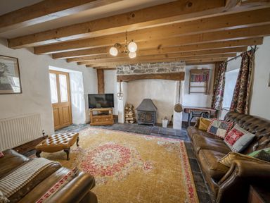 A living room with a fireplace and sofa at Cove Cottage Llangrannog