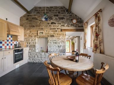 A kitchen with a table and chairs at Cove Cottage in Llangrannog
