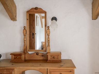 A wooden dresser with a mirror and lamp at Cove Cottage Llangrannog