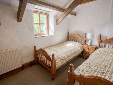 A bedroom with two beds and a window at Cove Cottage in Llangrannog