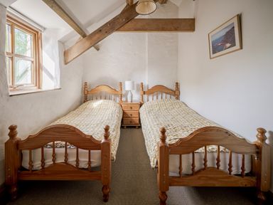 A bedroom with two single beds and a bedside table at Cove Cottage in Llangrannog