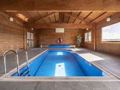An indoor pool with a bench and windows at Cove Cottage in Llangrannog