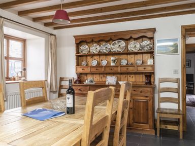 A dining room with a wooden table and hutch at Y Bwthyn in Llangrannog