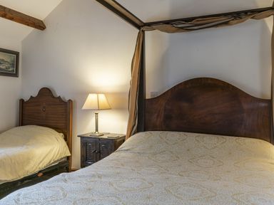 A bedroom with two beds and a lamp on a nightstand at Y Bwthyn in Llangrannog