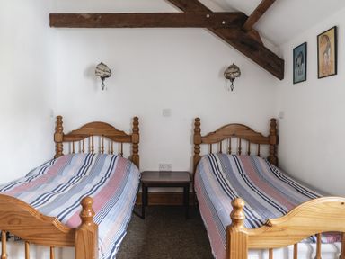 A bedroom with two beds and a bedside table at Y Bwthyn in Llangrannog