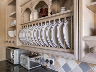 A kitchen with plates in a cabinet at Coach House in Llangrannog
