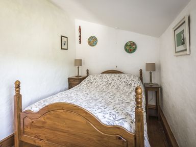 A bedroom with a wooden bed and bedside tables at Coach House Llangrannog