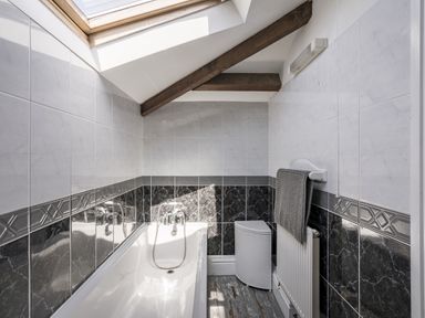 A bathroom with a bathtub and towel rack at Coach House in Llangrannog