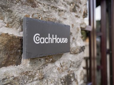 A sign with Coach House on a stone wall at Coach House in Llangrannog