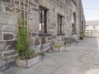 An outdoor area with stone wall and planters at Coach House in Llangrannog