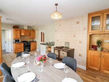 A kitchen with a dining table set for six and wooden cabinets at Teach Ards in Kilgarvan County Kerry