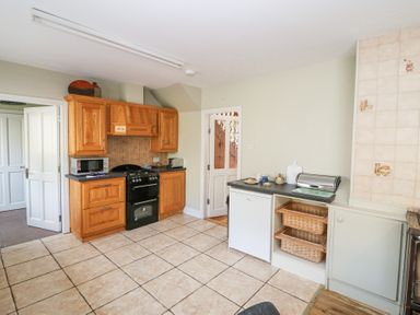 A kitchen with wooden cabinets a black stove microwave and a countertop with baskets at Teach Ards in Kilgarvan County Kerry