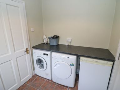 A laundry room with a washing machine dryer freezer iron and bucket at Teach Ards Kilgarvan County Kerry