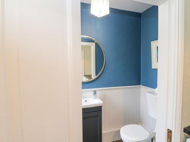 A bathroom with a toilet sink a round mirror and blue and white walls at Teach Ards Kilgarvan County Kerry