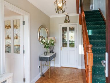 A hallway with a staircase and a console table with flowers at Teach Ards in Kilgarvan County Kerry