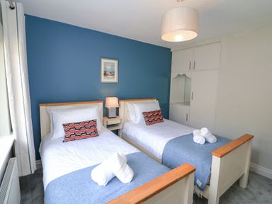 A bedroom with two single beds blue accent wall and white wardrobe at Teach Ards Kilgarvan County Kerry