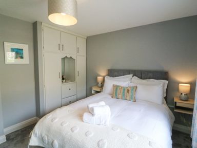 A bedroom with a bed with white bedding and pillows bedside tables with lamps and a built-in wardrobe at Teach Ards Kilgarvan County Kerry