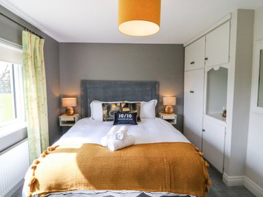 A bedroom with a bed with pillows and towels bedside tables lamps and built in cupboards at Teach Ards in Kilgarvan County Kerry