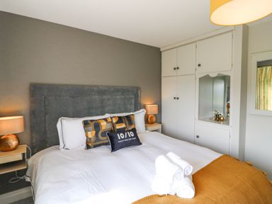 A bedroom with a double bed white sheets and pillows bedside tables with lamps built in wardrobes and folded towels on the bed at Teach Ards in Kilgarvan County Kerry