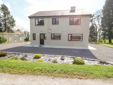 Exterior view of a two-story house with six windows and one door in front garden at Teach Ards in Kilgarvan County Kerry