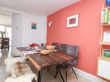 A dining area with a wooden table, chairs, a bench with a fur cover, and food on the table at Joymead in Malborough