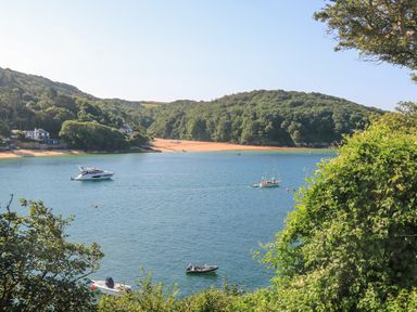 A body of water with several boats and forested hills in the background at Joymead in Malborough