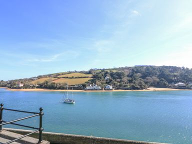 A coastal view with a sailboat on the water hills and houses on the shore at Joymead in Malborough