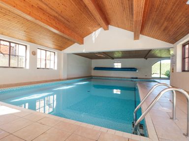 An indoor swimming pool with tiled floor and wooden ceiling at Beaver Cottage in Little Thirkleby near Thirsk