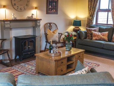 A living room with a fireplace armchairs coffee table and sofa at Beaver Cottage Little Thirkleby near Thirsk