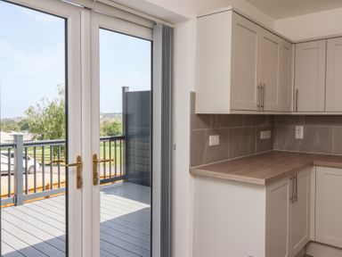 A kitchen with cabinets and double doors leading to a deck at Castle View in Scarborough