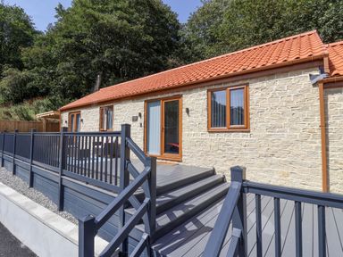 An outdoor area with a cottage and deck at Woodside in Scarborough