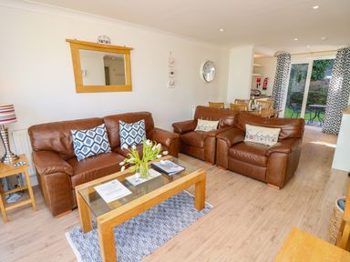 A living room with brown leather sofas a glass coffee table and a dining table with chairs at Cape A9 Norton Near Freshwater