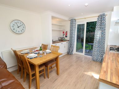 A dining area with a wooden table set for four and a kitchen with sliding doors leading outside at Cape A9 Norton Near Freshwater