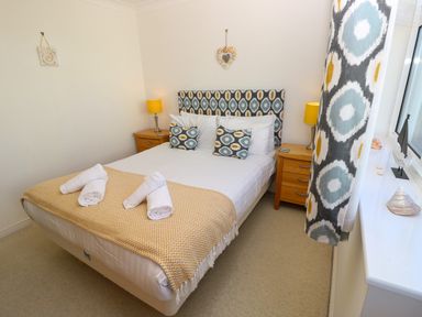 A bedroom with a double bed two bedside tables with lamps and patterned curtains at Cape A9 Norton Near Freshwater