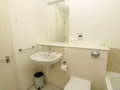 A bathroom with a sink mirror toilet toilet paper on holder and a small trash can at Cape A9 Norton Near Freshwater