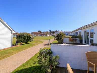 A pathway between white buildings with lawns and outdoor seating at Cape A9 Norton Near Freshwater