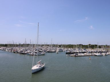 A marina with many docked sailboats and yachts and one sailboat sailing in the water at Cape A9 Norton Near Freshwater