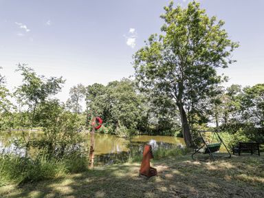 A garden with a pond, a swing and a bench at The Lodge