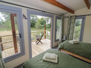 A bedroom with two beds and a view of the decking at Carps Well Lodge Hatton near Shrewley